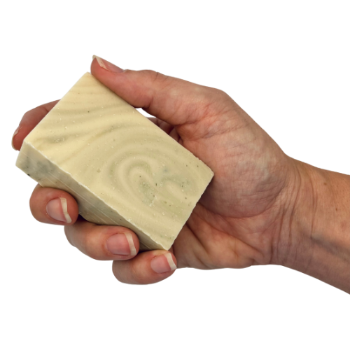 A hand holding a rectangular bar of soap with a swirled cream and light green pattern, isolated on a white background.