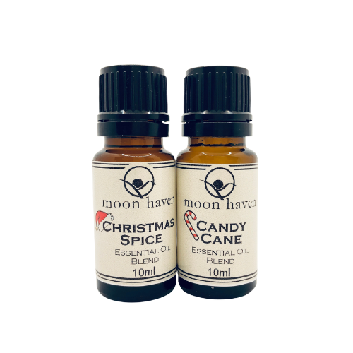 Two small brown bottles with black caps, labeled as 'Christmas Spice' and 'Candy Cane' essential oil blends from moon haven.